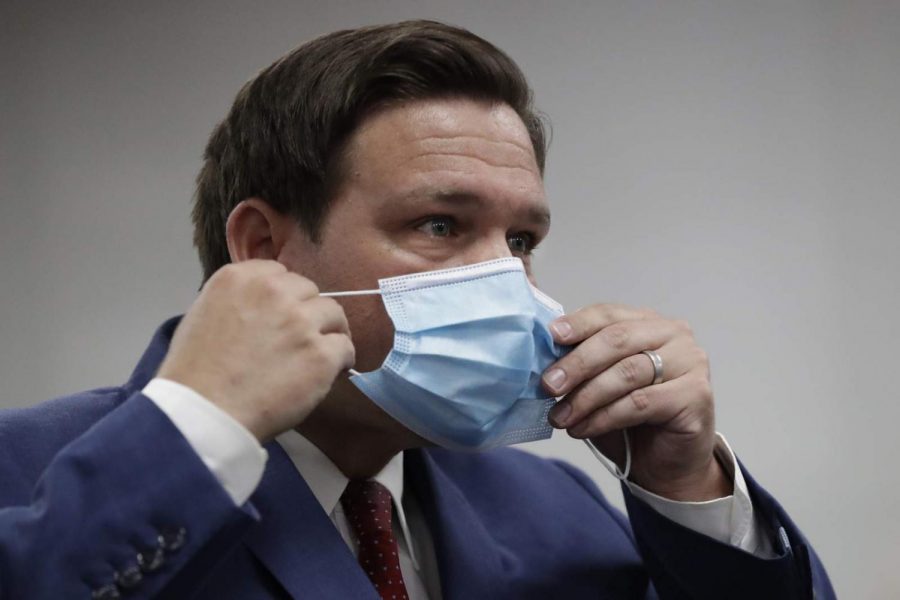 Florida Gov. Ron DeSantis puts on his mask as he leaves a news conference at Jackson Memorial Hospital.