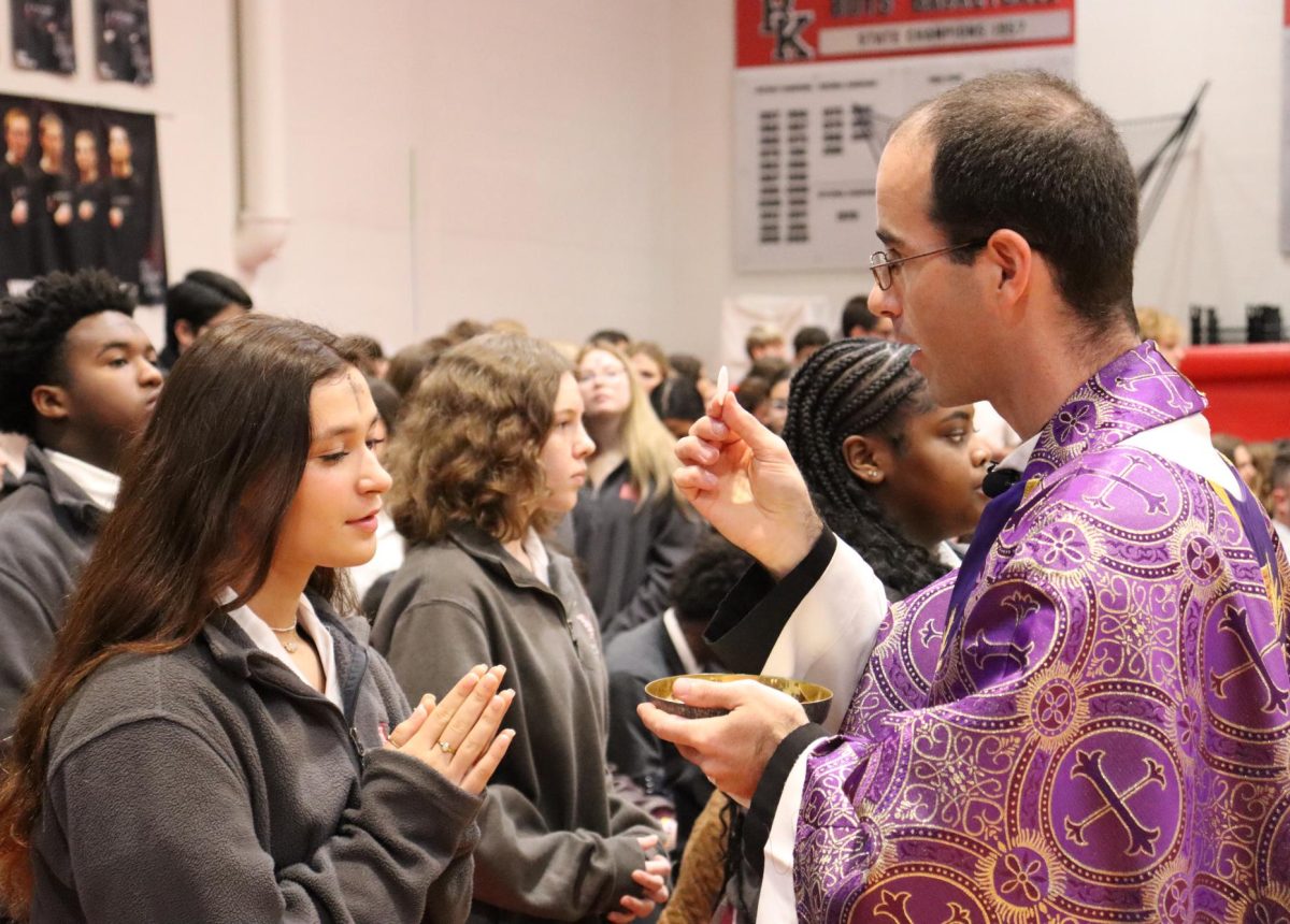 Father Peter offers communion to students.